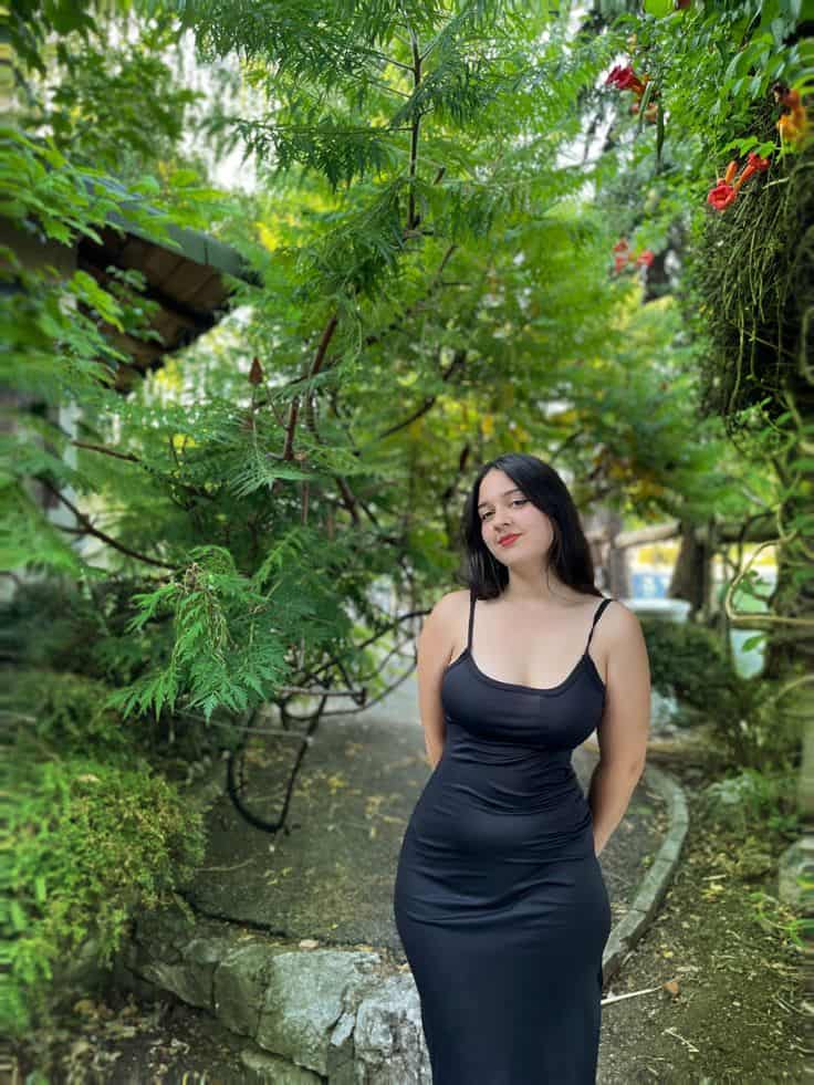 Mysterious dark-eyed escort leaning against wall for seductive meeting